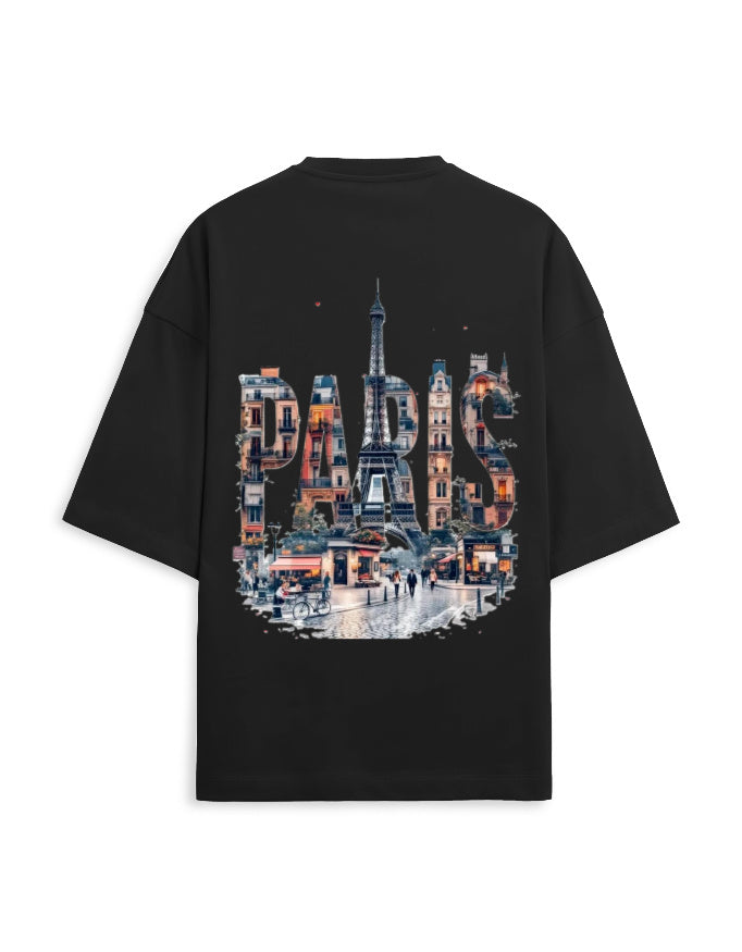 A black oversized short-sleeve t-shirt shown from the back, featuring a large graphic print of the Eiffel Tower and Parisian street scene with the word 'PARIS' in architectural shapes.