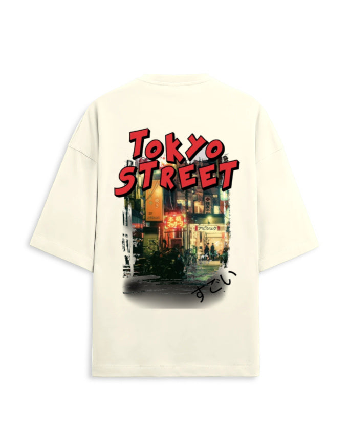 An oversized cream-colored t-shirt shown from the back, featuring a large graphic print of a Tokyo street scene with 'TOKYO STREET' written in bold red letters.
