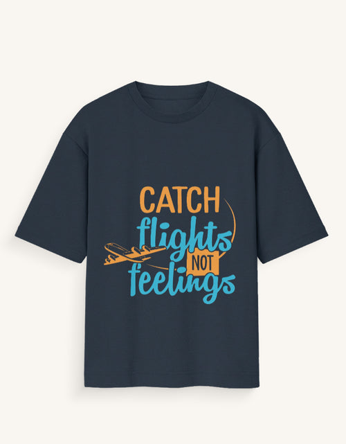 Front view of a dark navy blue unisex oversized streetwear t-shirt featuring a stylized airplane graphic and the text "CATCH FLIGHTS NOT FEELINGS" in orange and teal lettering across the center.