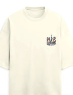 An off-white short-sleeve crewneck t-shirt featuring a small graphic on the left chest that spells 'PARIS' in a collage of Parisian landmarks, including the Eiffel Tower.
